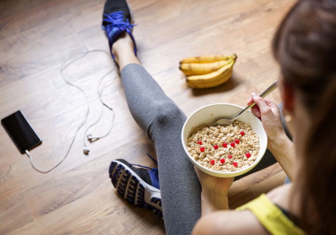 Young girl eating a oatmeal with berries after a workout . Fitness and healthy lifestyle concept.